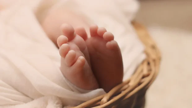 رضيع يمسك بإصبع شخص بالغ كرمز للعناية الصحية والأثر التنموي